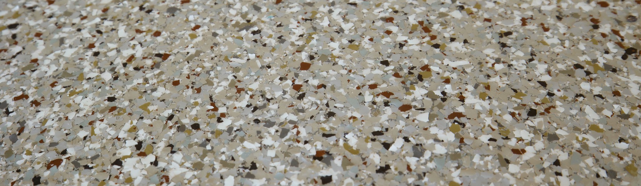 Close view of a finished floor in a cream, tan and grey flake blend under a gloss top coat